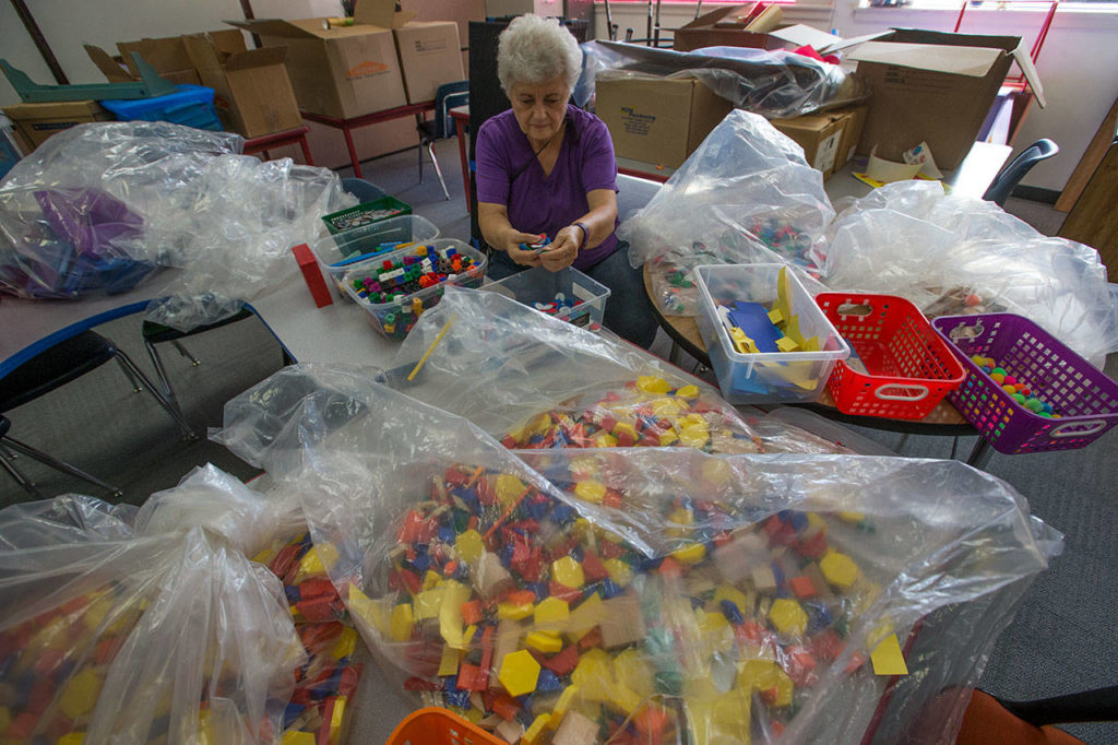 Volunteer Gena Graham sorts bags of items used for math tutoring as she and others get classes ready. (Andy Bronson / The Herald)
