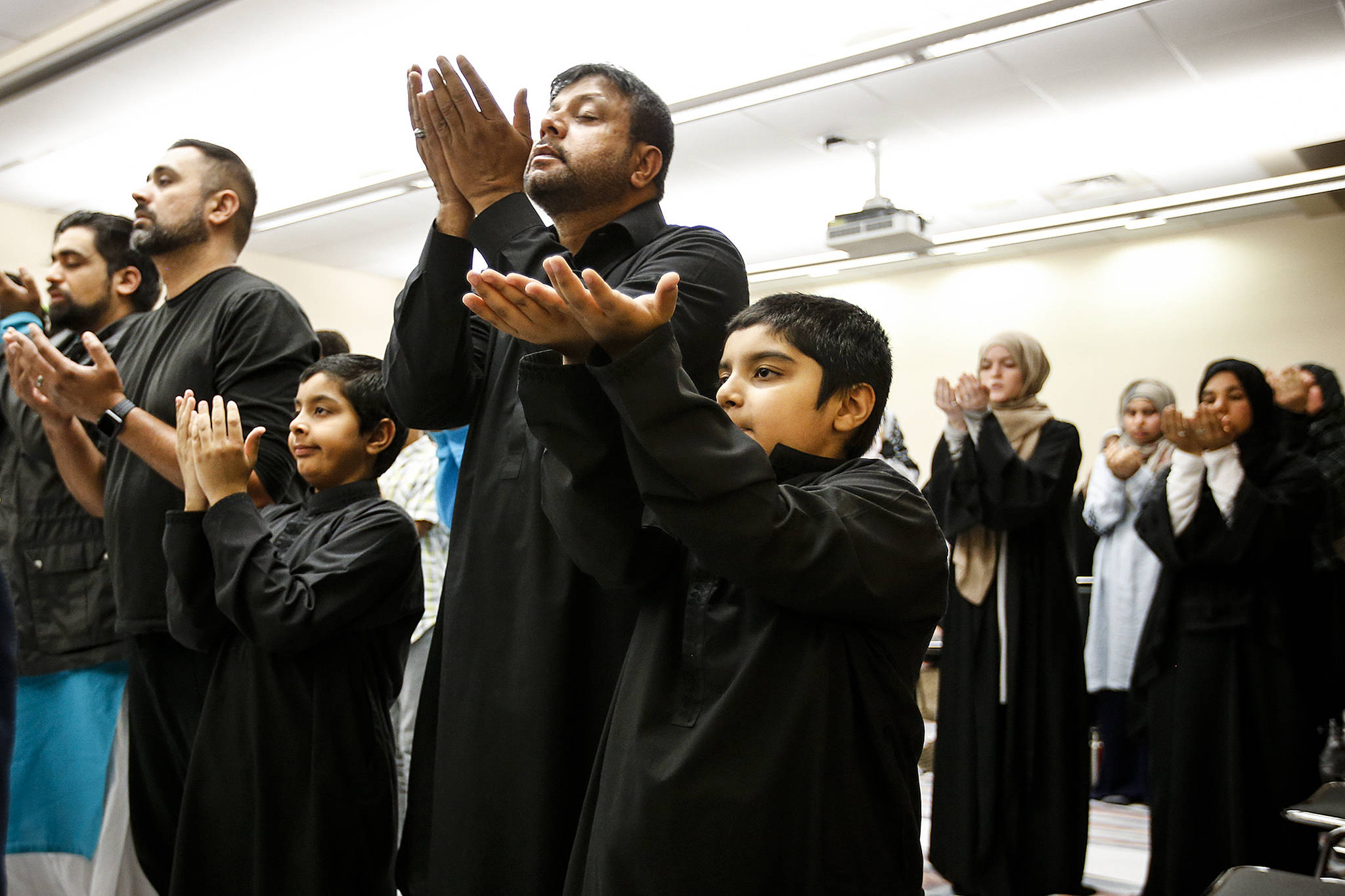 Ghulam Abbas (center) prays with his two sons Ammar (left), 8, and Ayaan, 8, during an evening service for the Zainab Center at the Lynnwood Convention Center on Thursday, Aug. 31. The center, which serves Shiite Muslims, is temporarily using the convention center’s facilities while they await permits to begin repairing their water-damaged building in Lynnwood. (Ian Terry / The Herald)