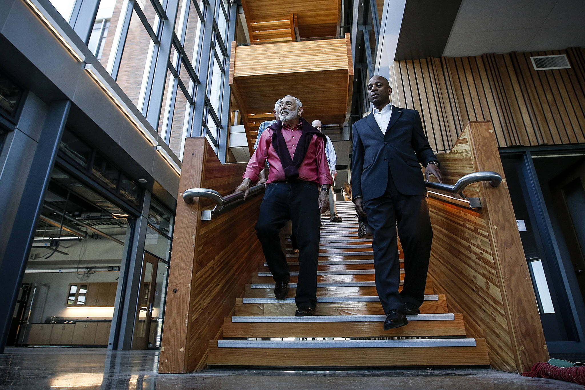 Dr. Larry Schecter (left), associate dean for WSU North Puget Sound’s medical education programs, walks down the central staircase with Chancellor Paul Pitre in the new building that houses the medical school’s programs in Everett. The tour for incoming medical school staff took place on May 20. (Ian Terry / Herald file)