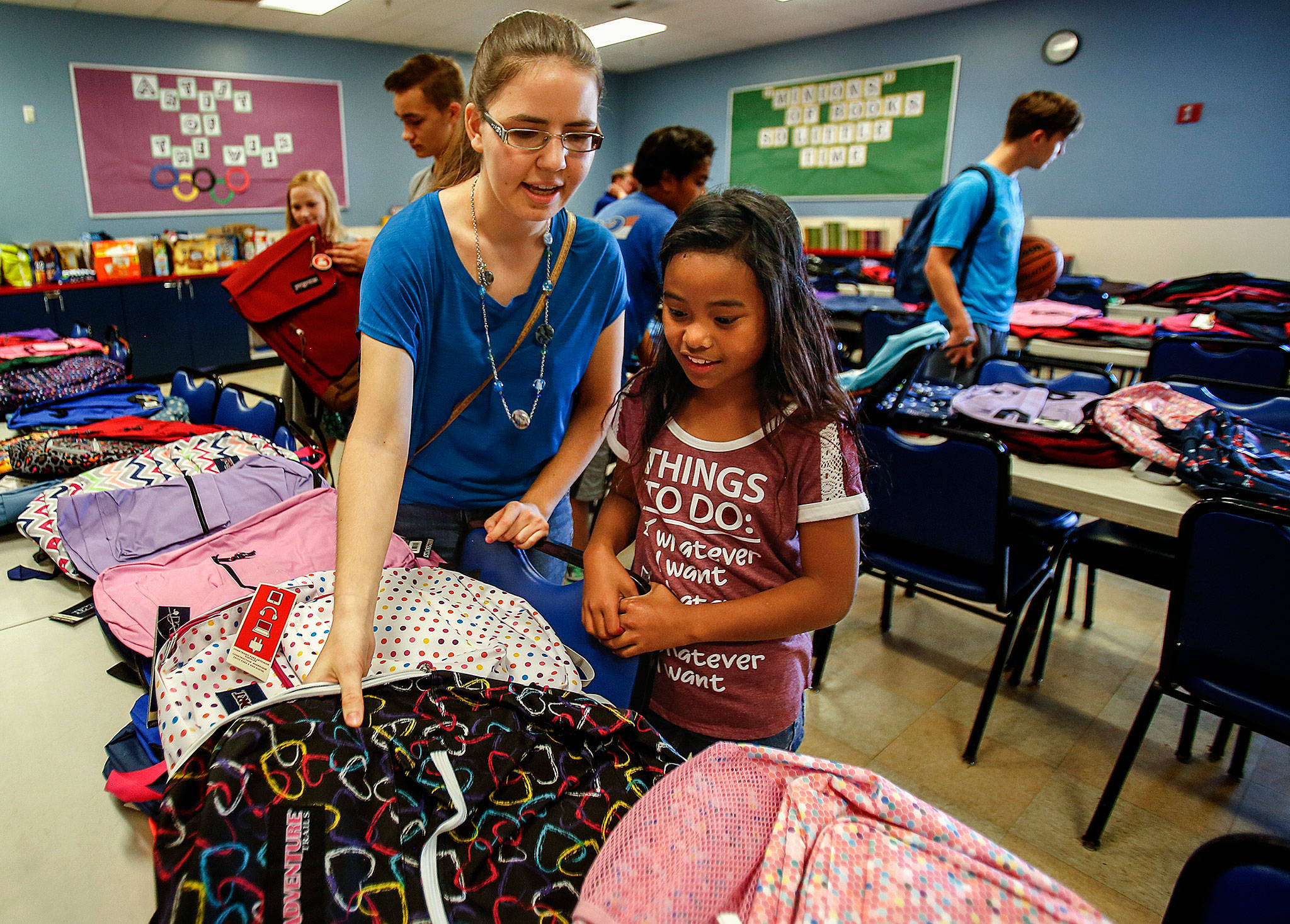 Rachel Preston helps Jailey Henson, 10, pick out a brand new backpack for school Thursday at the Everett Boys & Girls Club. Preston recently joined a new Rotary club for young people wanting to get involved and help out in the community. (Dan Bates / The Herald)