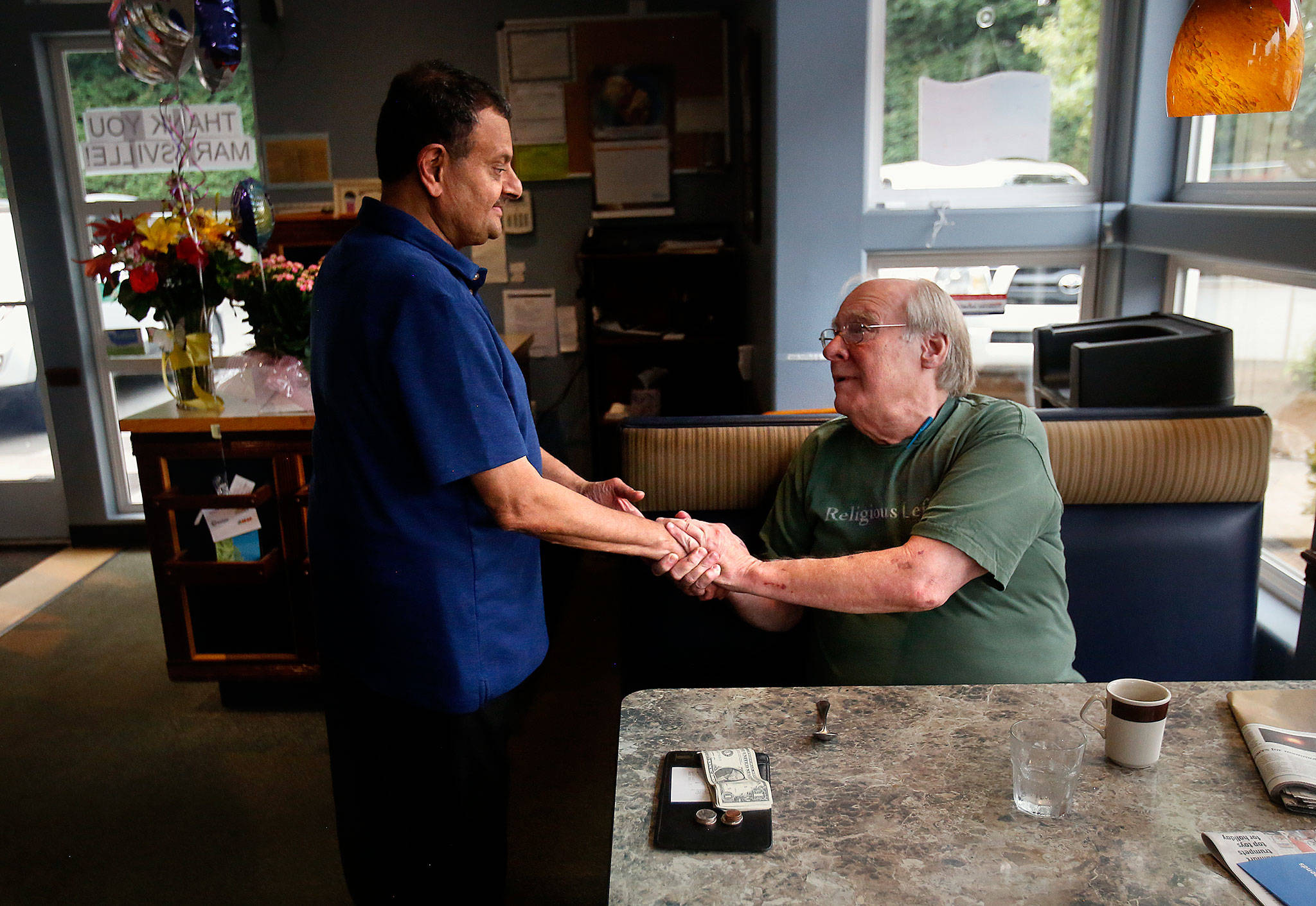 After finishing his breakfast, David Black, right, a long-time customer with high praise for the Balas, takes Shabbir Bala’s hand to thank him before leaving Boondockers on their final day of operation Wednesday. (Dan Bates / The Herald)