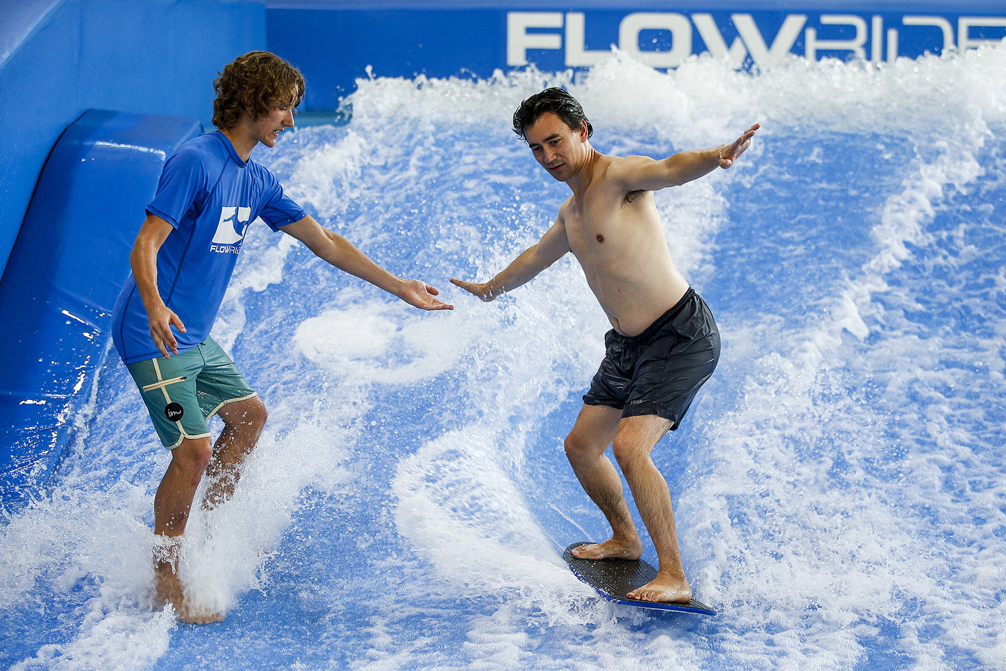 Herald columnist Nick Patterson (right) tries out the Flowrider with the help of instructor Evan Campbell at the Snohomish Aquatic Center on Tuesday, Aug. 29. (Ian Terry / The Herald)