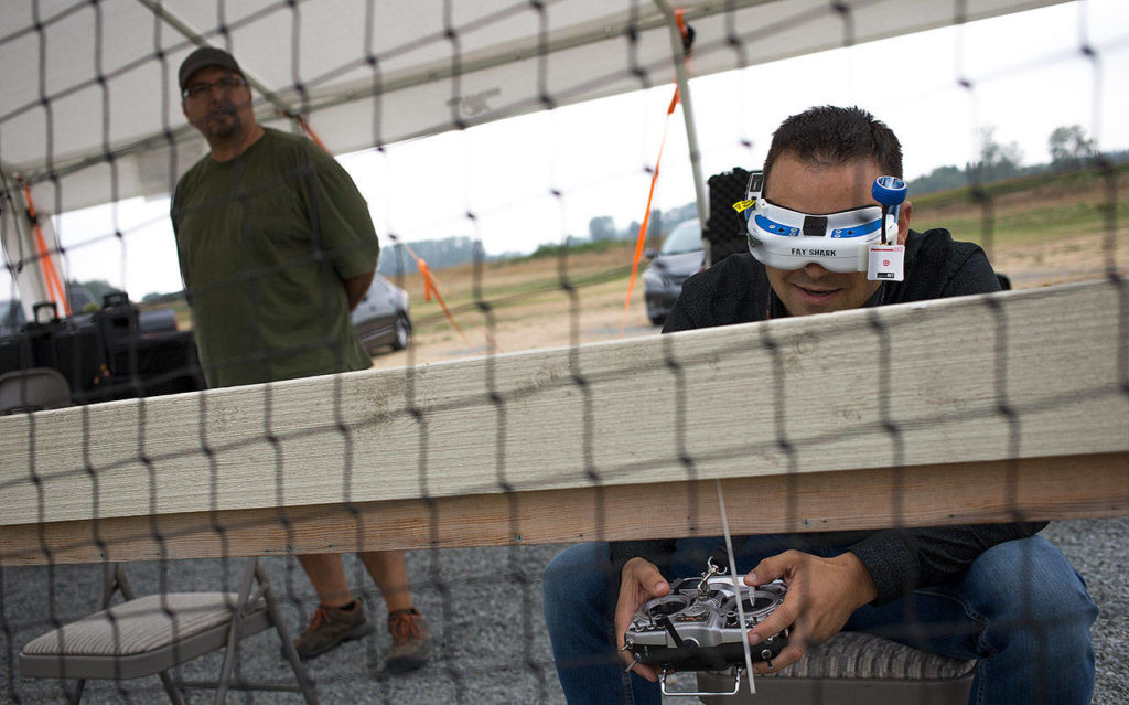 Brett Wilson watches the drone Friday as Nathan Sutton flies it using VR goggles at a course at DieHard RC Park in Snohomish. (Andy Bronson / The Herald)

