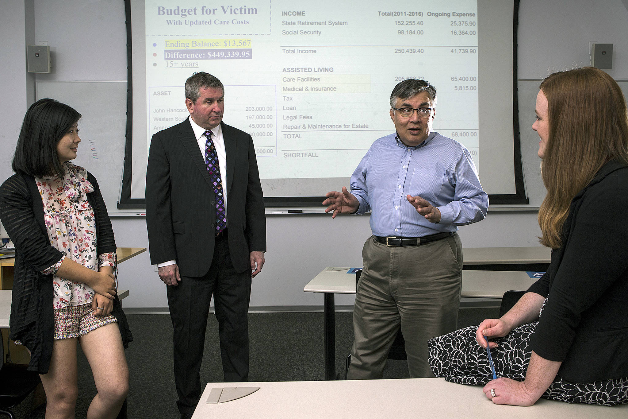 University of Washington Bothell’s forensic accounting class students Yiya You (left) and Rochelle McElroy (right) talk with professor Rajib Doogar (center right) and class mentor Kenneth Hines, a former IRS investigator. (Ian Terry / The Herald)