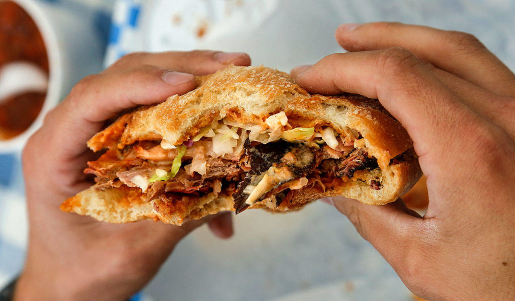 Customer Adam Chapman devours a barbecue sandwich at the Old School BBQ. Dan Bates / The Herald
