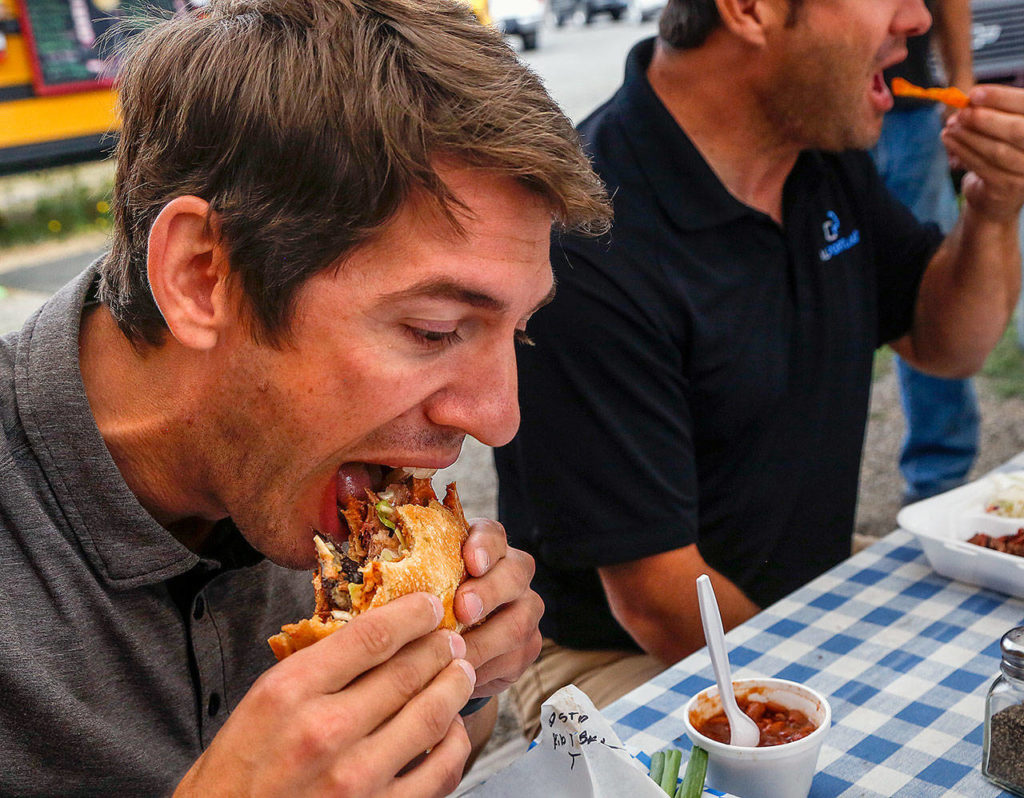 Customers Adam Chapman (left) and Ed Harrison chow down at the Old School Bus BBQ. Dan Bates / The Herald
