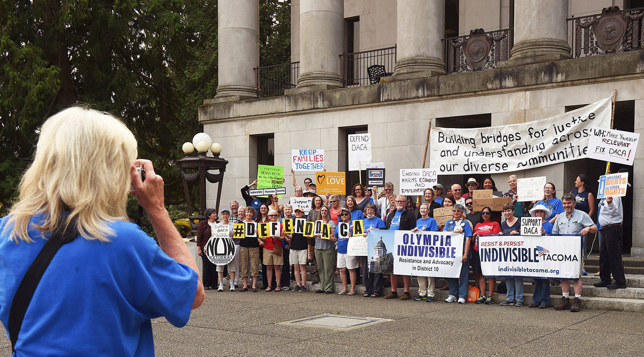 Carla Wulfsburg takes a photo of fellow Olympia Indivisible supporters and other organizations during a gathering in front of the Insurance Building on the Capitol campus in Olympia on Thursday, in protest of the Trump administration’s action against the Deferred Action for Childhood Arrivals program. (Steve Bloom / The Olympian)