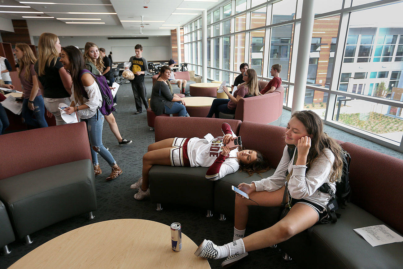 Finding a spot on the new couches in the library, juniors Kylee Ditto and Mia Barrio check their phones as they take a tour, then attend class, at the new Lakewood High School building on Wednesday in Lakewood. (Andy Bronson / The Herald)