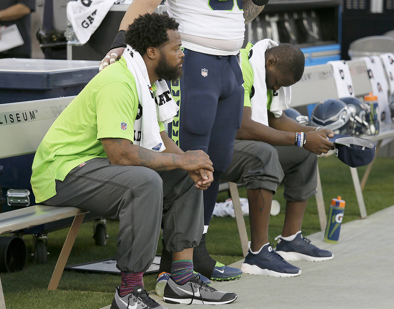 In this Aug. 31 photo, Seattle Seahawks defensive end Michael Bennett (left) sits during the playing of the national anthem next to Justin Britt (center) and another teammate before an NFL preseason football game between the Raiders and the Seattle Seahawks in Oakland, California. (AP Photo/Eric Risberg,File)