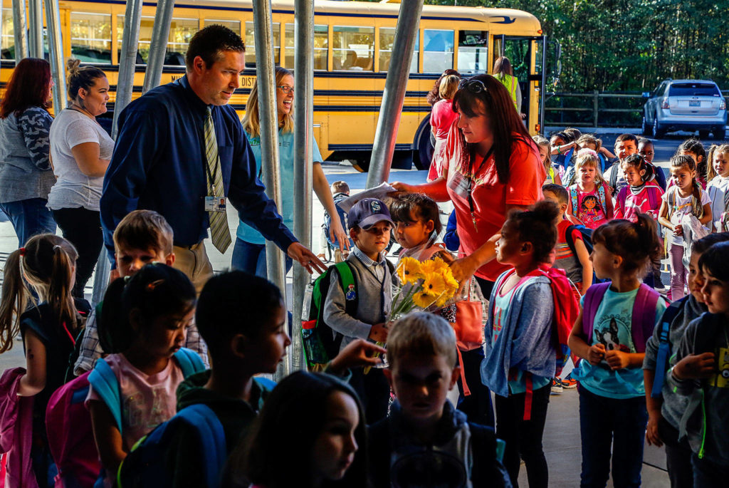 Mukilteo school district staff Josh Benedict (shirt & tie) Keri Oxner (center) and Jackie Marino (right), along with others, greet and help direct hundreds of kindergarten students Monday morning as they arrive at the new Pathfinder Kindergarten, a unique, all-day, all-kindergarten school available to kids district-wide. (Dan Bates / The Herald)
