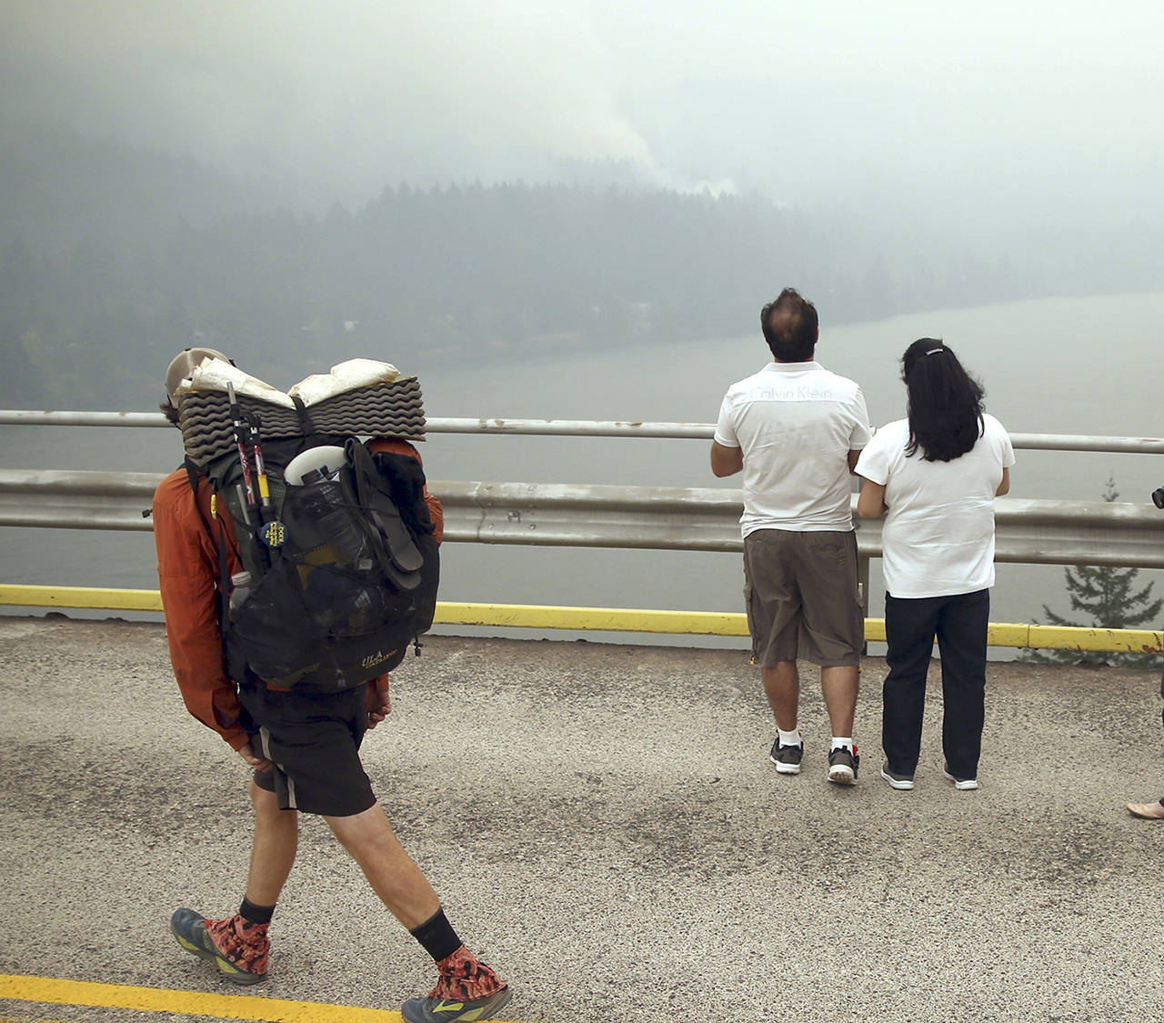 A hiker and two others look at smoke from the Eagle Creek wildfire on the Oregon side of the Columbia River Gorge from the Bridge of the Gods, spanning the Columbia River between Washington and Oregon states, near Stevenson, Washington, on Wednesday. (AP Photo/Randy L. Rasmussen)
