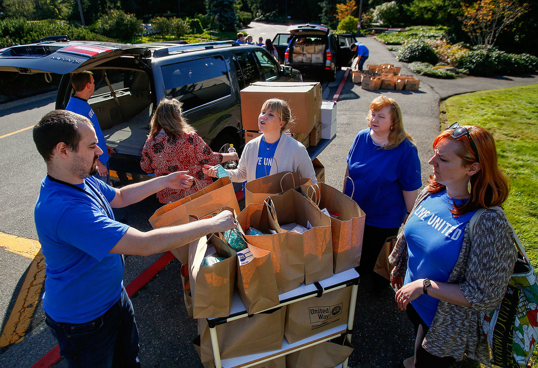 Fluke Corp.’s Susan Israel (center) assists with other Fluke employees including William Nelson (left) and Allyce Barry (right), in efforts to load 260 new-mom kits into vehicles outside the company Friday morning. Workers volunteered with United Way’s Day of Caring. (Dan Bates / The Herald)
