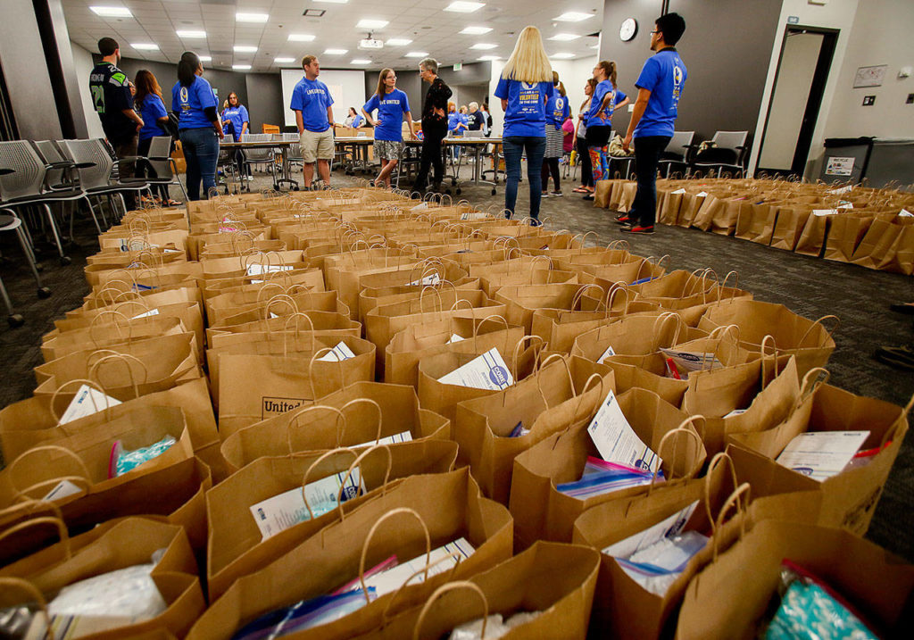 Having created 260 new-mom kits, complete with everything from diapers to “The Very Hungry Caterpillar” books, Fluke employees await fellow volunteers in SUVs Friday morning. They volunteered as part of United Way’s Day of Caring. (Dan Bates / The Herald)
