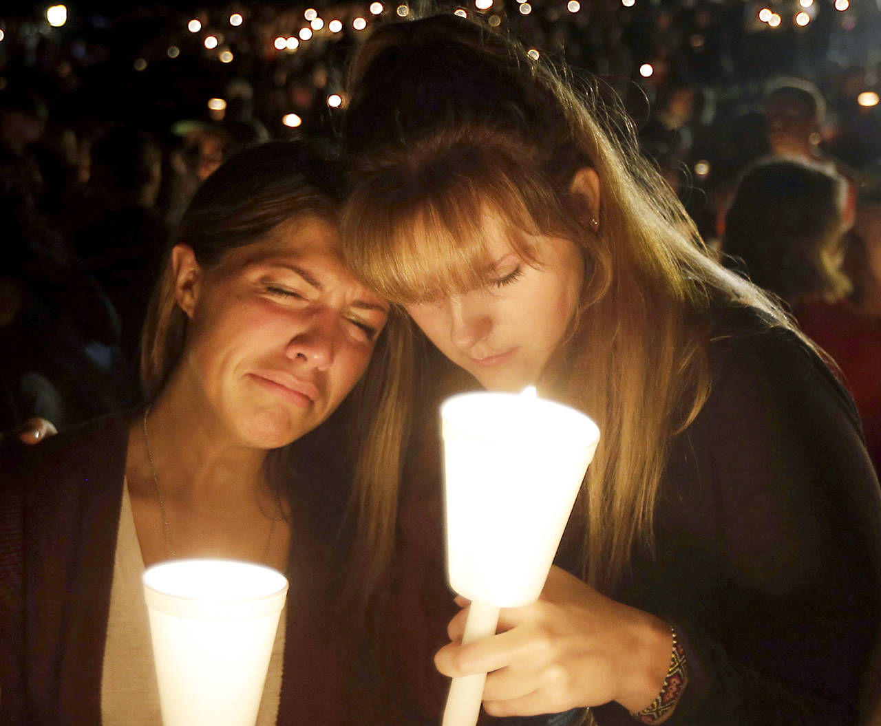 In this Oct. 1, 2015, photo, Kristen Sterner (left) and Carrissa Welding, both students at Umpqua Community College, embrace each other during a candlelight vigil for those killed during a shooting at the college in Roseburg, Oregon. (AP Photo/Rich Pedroncelli, file)