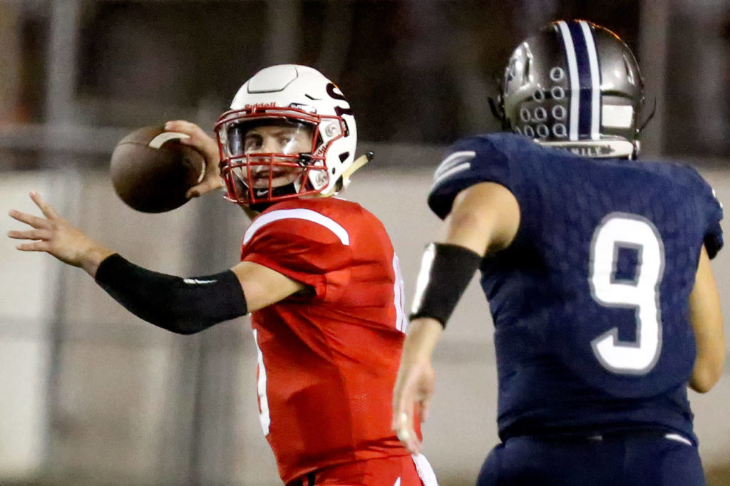 Snohomish quarterback Langdon Orgill drops back to pass with Glacier Peak’s Juhno Lindsay bearing down during the Grizzlies’ 28-14 win over the Panthers in a cross-town rivalry matchup at Veterans Memorial Stadium in Snohomish. (Kevin Clark / The Herald)
