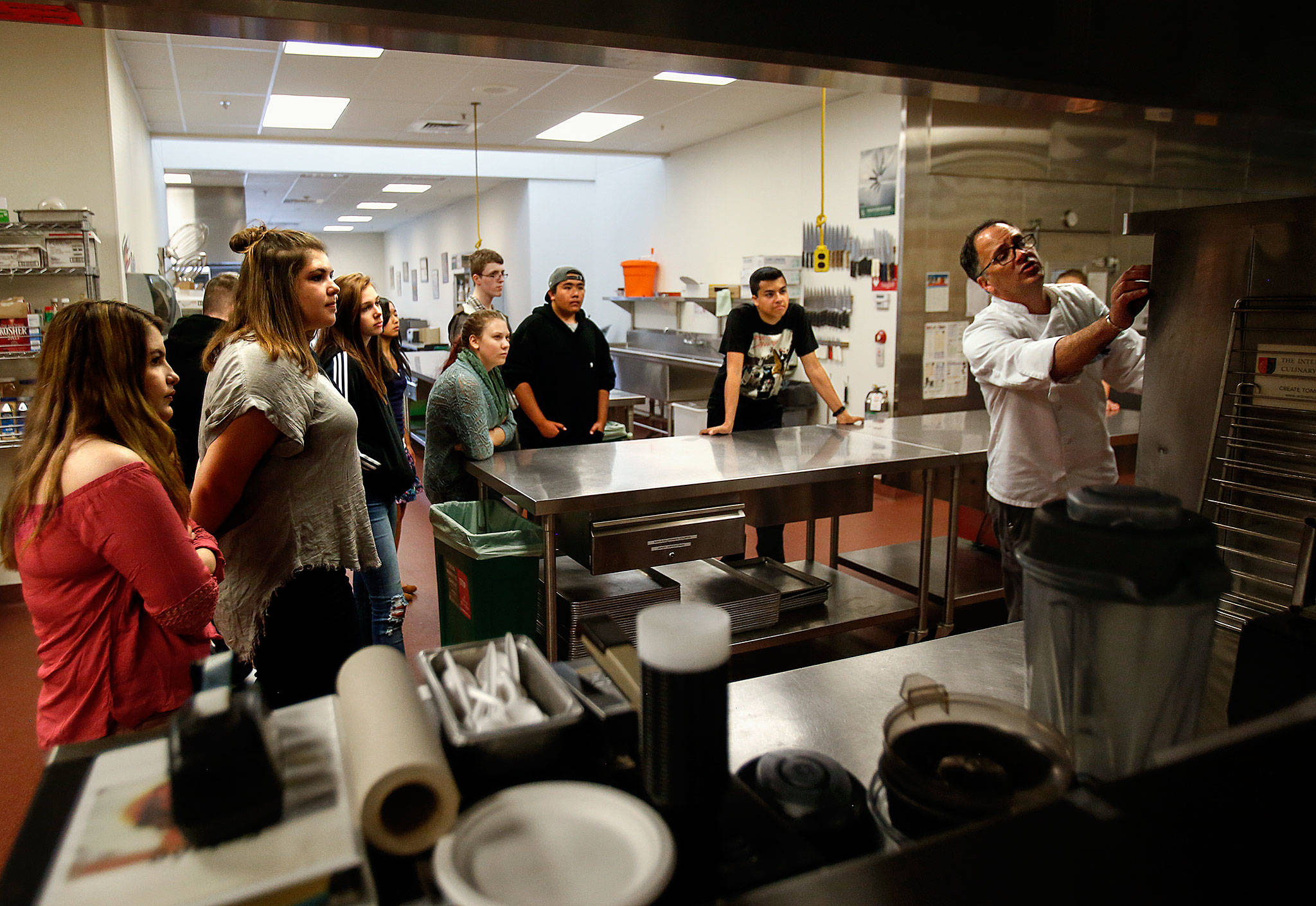 In culinary arts class at Sno-Isle Tech Center Wednesday, instructor John Pence introduces new students to unusually large kitchen appliances, including the ovens, one of which he demonstrates at right. (Dan Bates / The Herald)