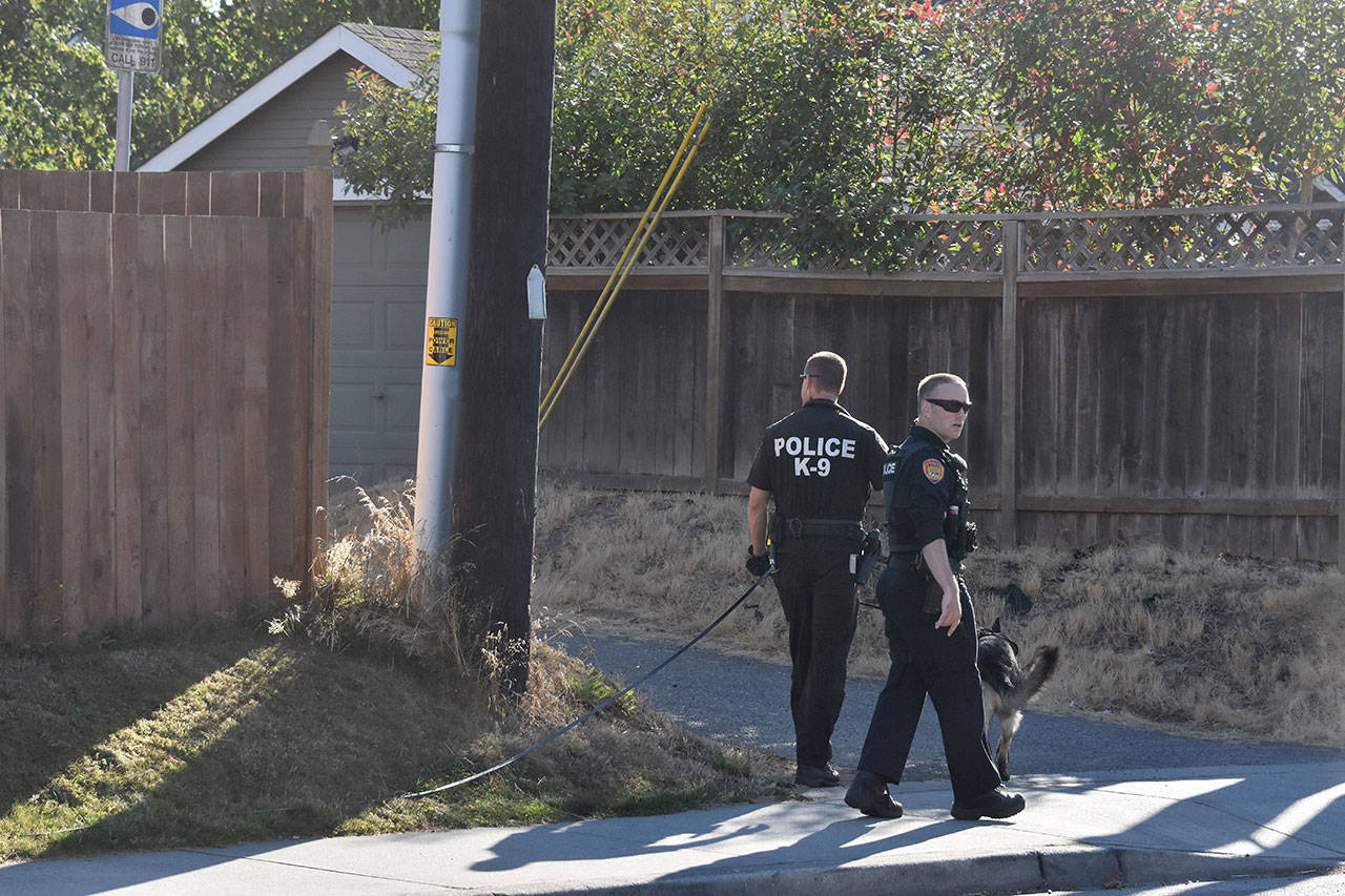 Everett police search the neighborhood north of Providence Regional Medical Center on Tuesday afternoon, after a shooting injured a 19-year-old man north of the hospital. (Caleb Hutton / The Herald)