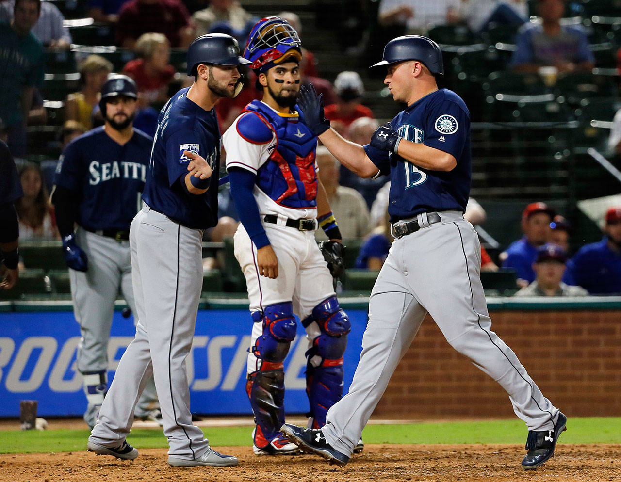 The Mariners’ Yonder Alonso congratulates Kyle Seager (right) on his three-run home run as Rangers catcher Robinson Chirinos watches during the third inning of a game Sept. 12, 2017, in Arlington, Texas. (AP Photo/Tony Gutierrez)