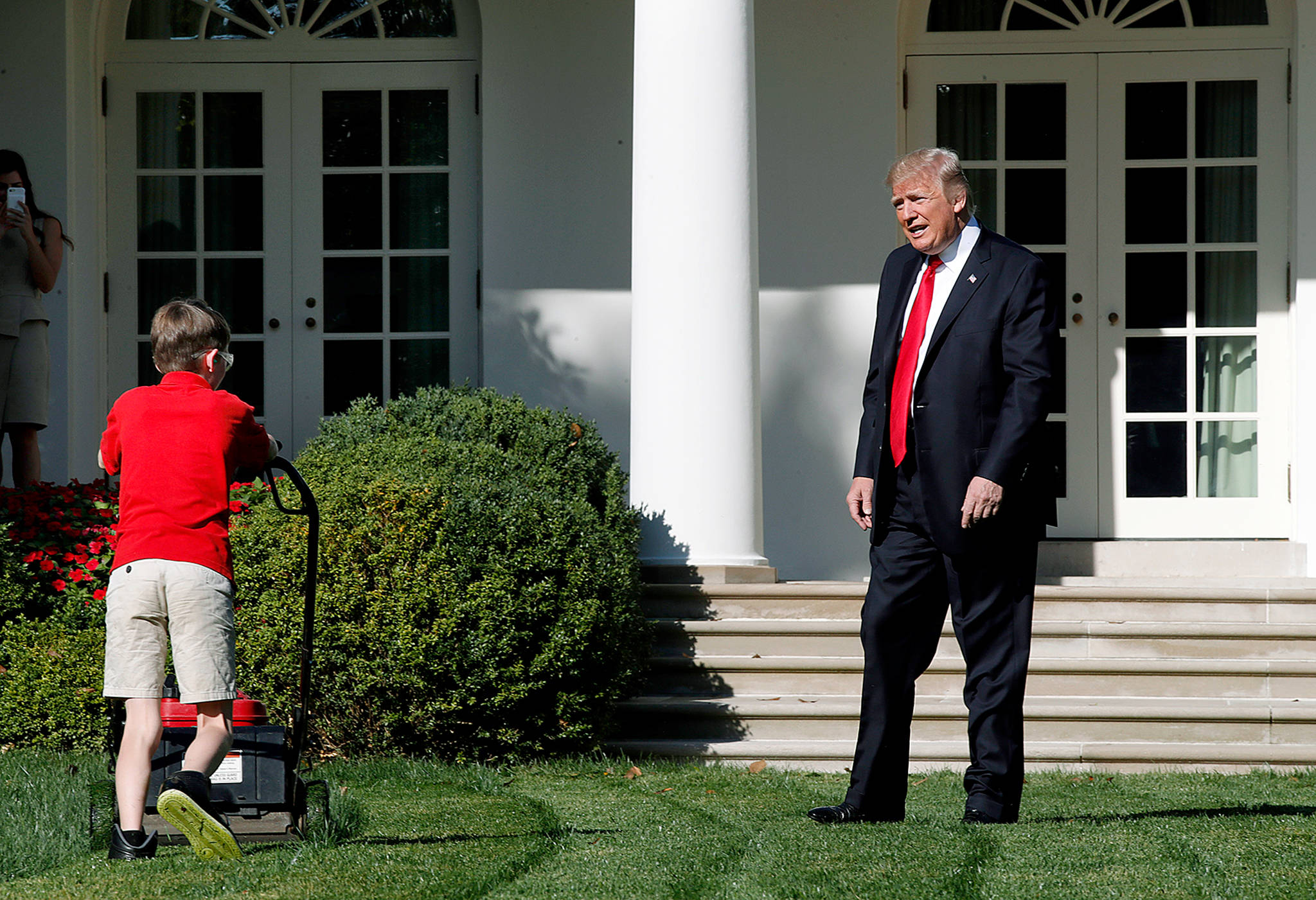 Frank Giaccio, 11, of Falls Church, Virginia, is surprised by President Donald Trump on Friday as he mows the lawn of the Rose Garden at the White House in Washington. The 11-year-old was focused on the job at hand and didn’t notice the president until he was right next to him. (AP Photo/Jacquelyn Martin)