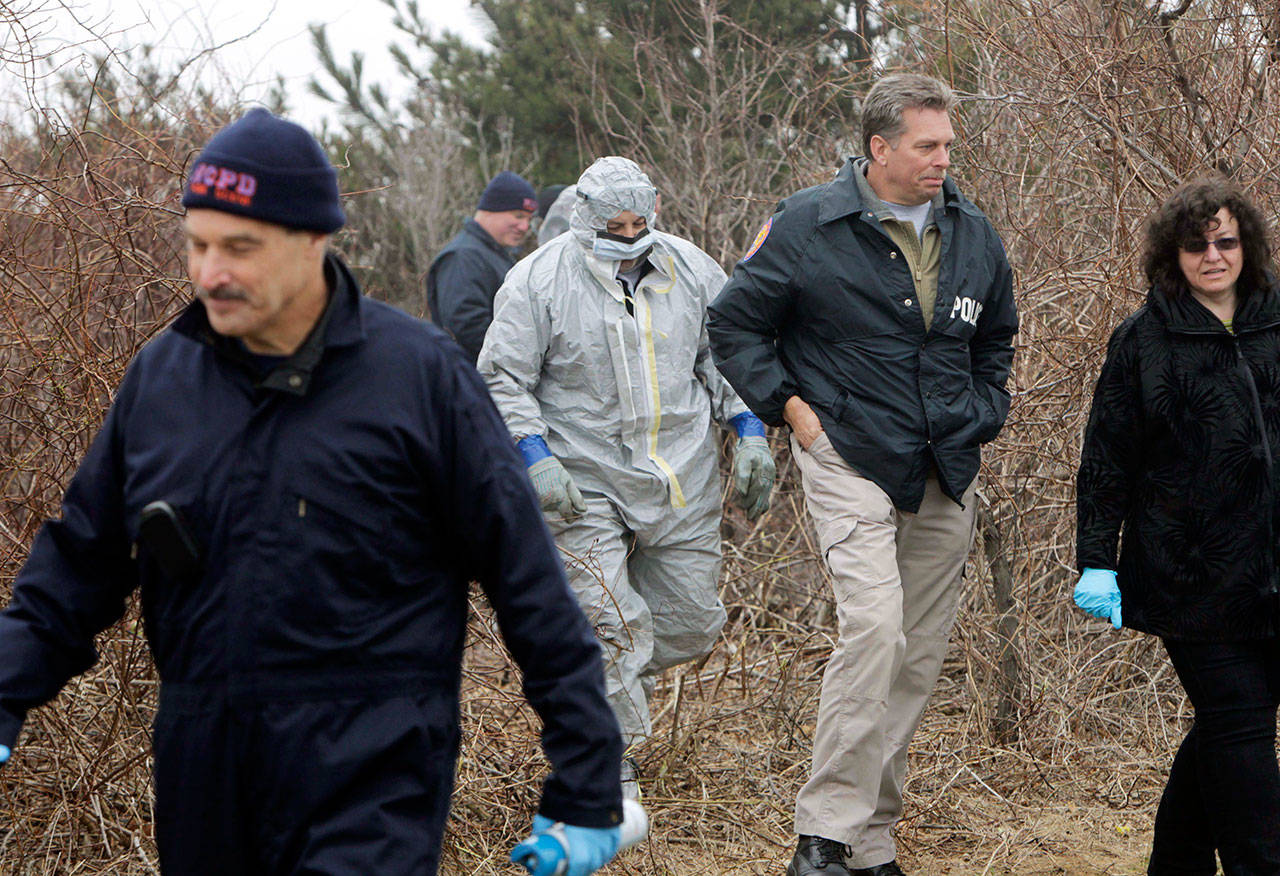 In this April 11, 2011, file photo, emergency personnel search through the brush for human remains near Jones Beach in Wantagh, N.Y. On Tuesday, Sept. 12, 2017, Suffolk County Assistant District Attorney Robert Biancavilla said after the sentencing of Long Island carpenter John Bittrolff for killing two prostitutes in the early 1990s, that Bittrolff may be responsible for killing at least one of 10 victims whose remains have been found along a Long Island beach highway. (AP Photo/Seth Wenig, File)