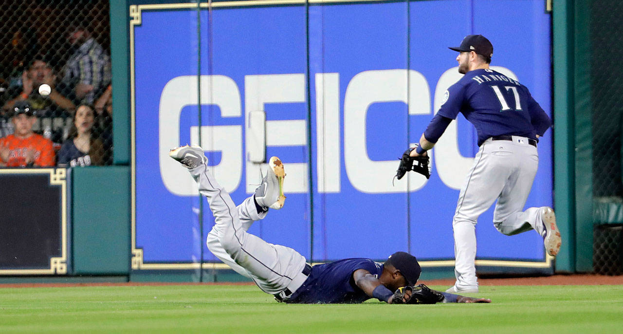 Seattle’s Guillermo Heredia (left) falls after trying to make a diving catch on a double by Houston’s George Springer as right fielder Mitch Haniger chases after the ball during the fourth inning of Saturday’s game in Houston. (AP Photo/David J. Phillip)