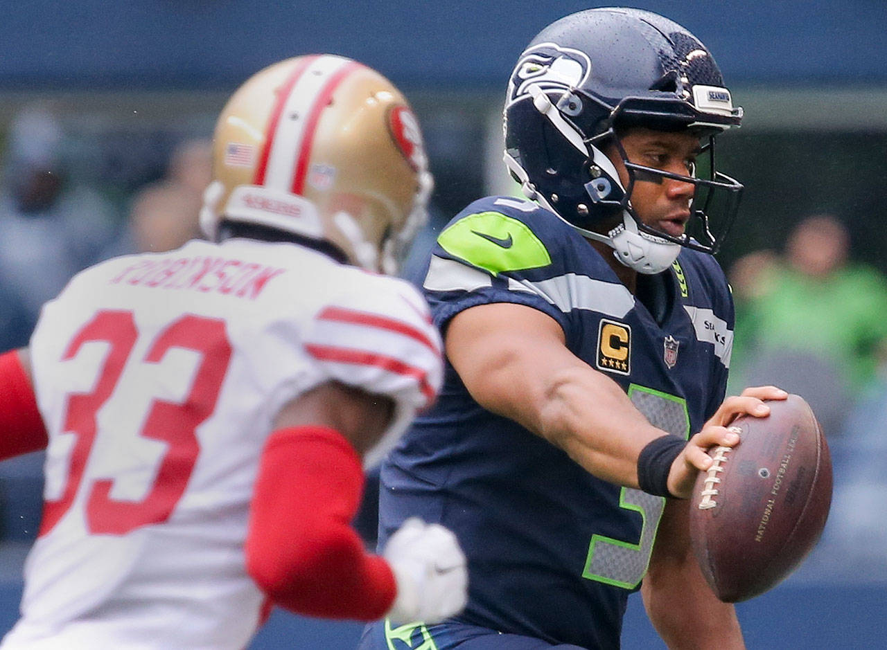 Seahawks quarterback Russell Wilson reaches for additional yardage with 49ers cornerback Rashard Robinson closing in during Sunday’s game at CenturyLink Field in Seattle. (Kevin Clark / The Herald)