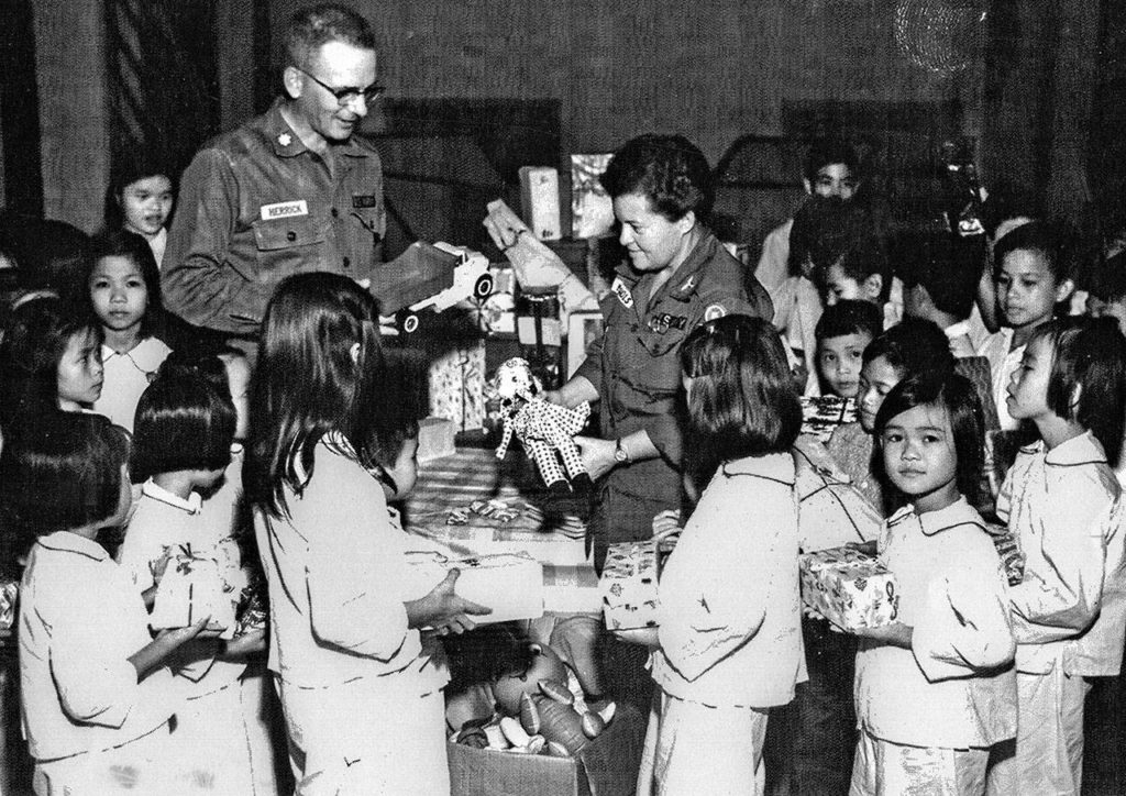 Army nurse Barbara Jean Nichols, who later rose to the rank of lieutenant colonel, and another officer distribute gifts at an orphanage in Saigon in the 1960s during the Vietnam War. (Nichols collection photos)
