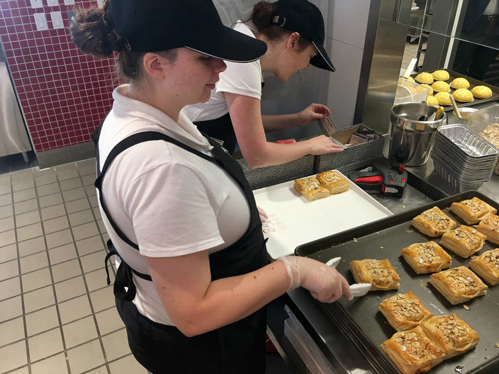 Staff Stranjay Wahl (foreground) and Jesika Foster prepare pastries for the grand opening of 85°C Bakery Cafe in Lynnwood. (Jim Davis/HBJ)
