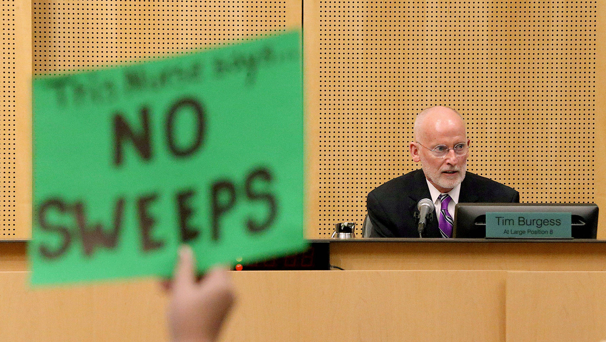 A protester holds a sign as Seattle City Council member Tim Burgess speaks. He was chosen on Monday by the Seattle City Council to be temporary mayor. (Ken Lambert/The Seattle Times via AP)