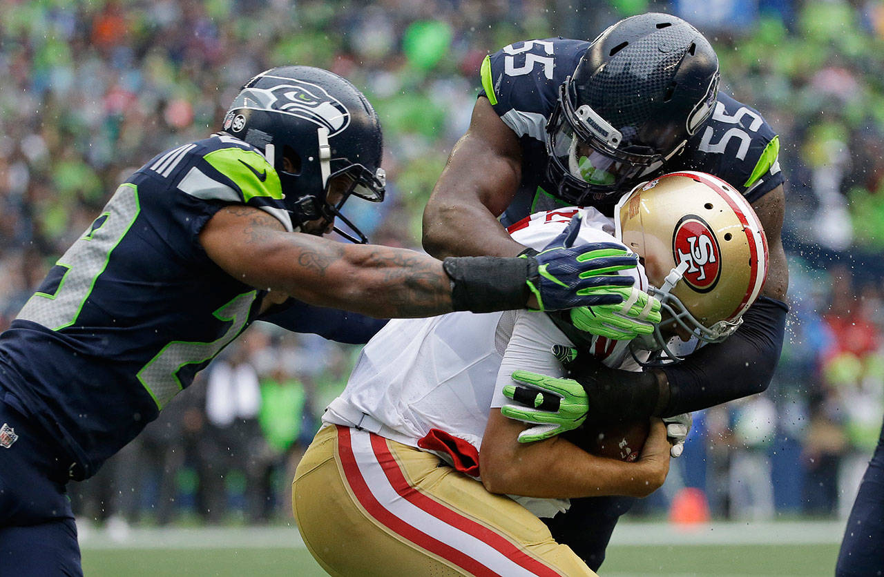 Seahawks defensive end Frank Clark (55) sacks 49ers quarterback Brian Hoyer as free safety Earl Thomas (left) closes in during the second half of a game Sept. 17, 2017, in Seattle. (AP Photo/Elaine Thompson)