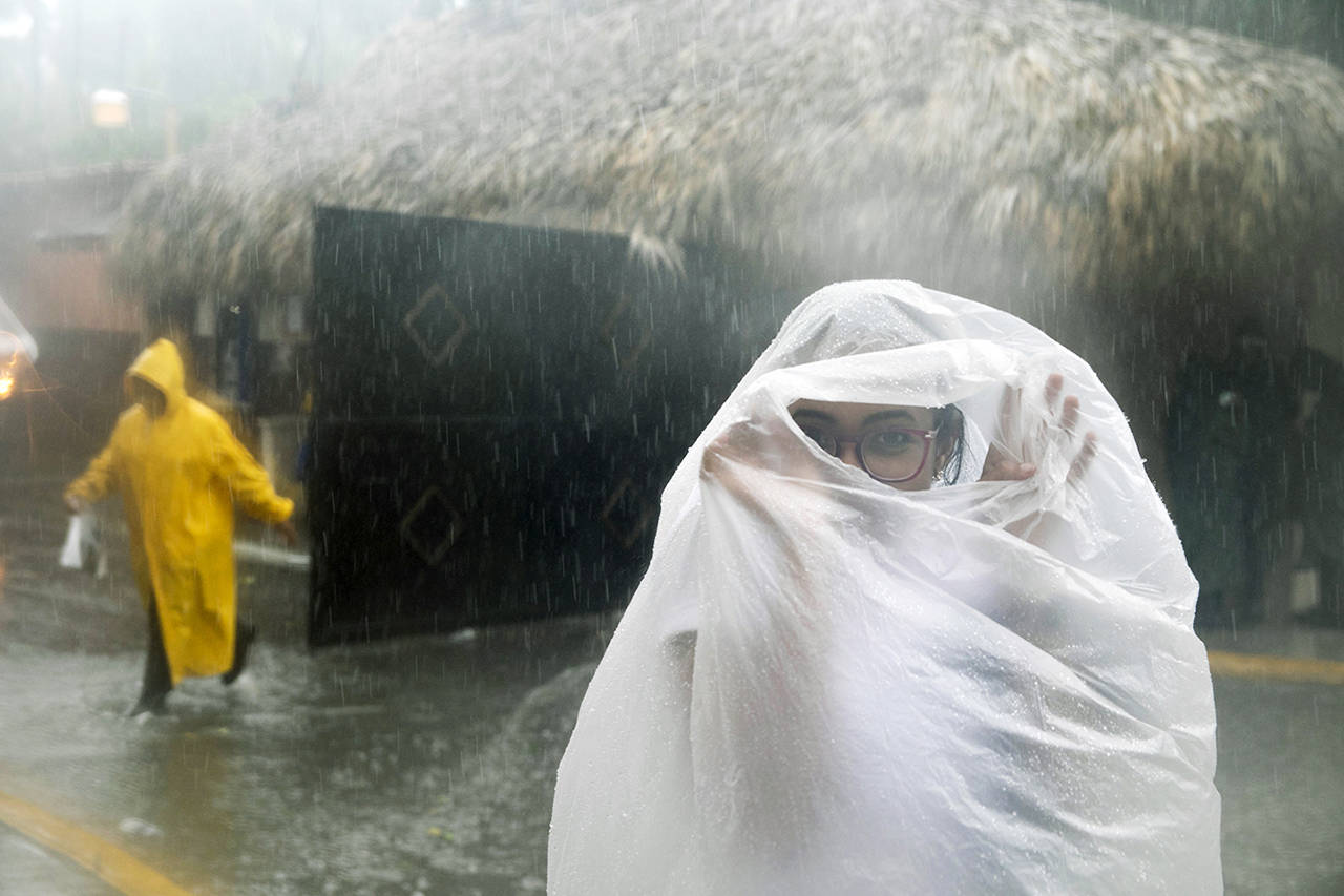 A woman covers herself with a plastic bag as she makes her way to work as Hurricane Maria approaches the coast of Bavaro, Dominican Republic, on Wednesday. (AP Photo/Tatiana Fernandez)
