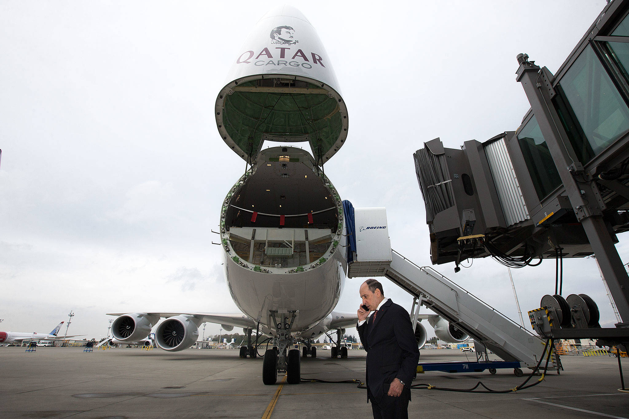 Akbar Al Baker, the CEO of Qatar Airways, talks on his cell phone in front of a Boeing 747-8 cargo plane bearing the company’s maroon logo after a signing ceremony at the Boeing Delivery Center on Monday, Sept. 25, 2017 in Everett, Wa. Qatar Airways took the delivery of their first 747-8 freighter. (Andy Bronson / The Herald)