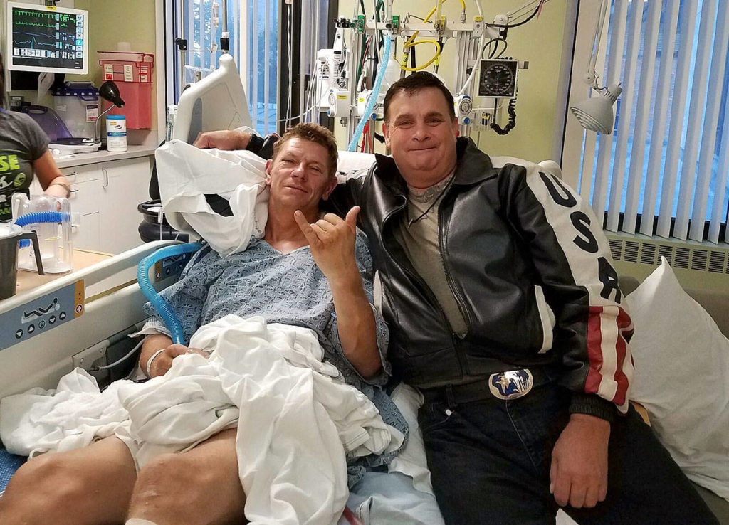 Christian Schimandle and Byron Petit pose together at Schimandle’s hospital bed at Harborview Medical Center in Seattle. Schimandle was found by Petit after his truck went of a cliff northwest of Darrington. (Photo Courtesy Byron Petit)
