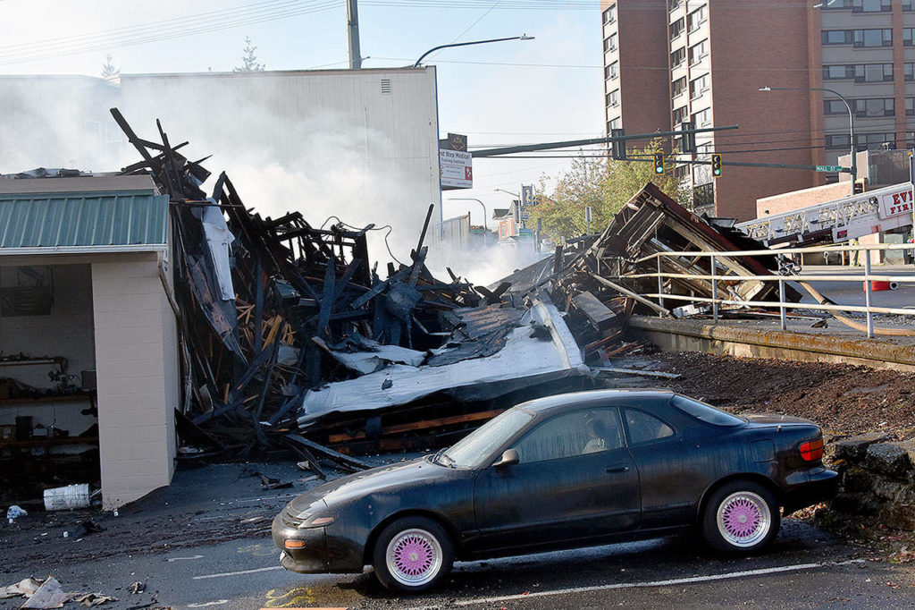 A massive fire at a furniture store filled downtown Everett with smoke Monday night. The building continued to smolder well after daybreak Tuesday. (Caleb Hutton / The Herald)
