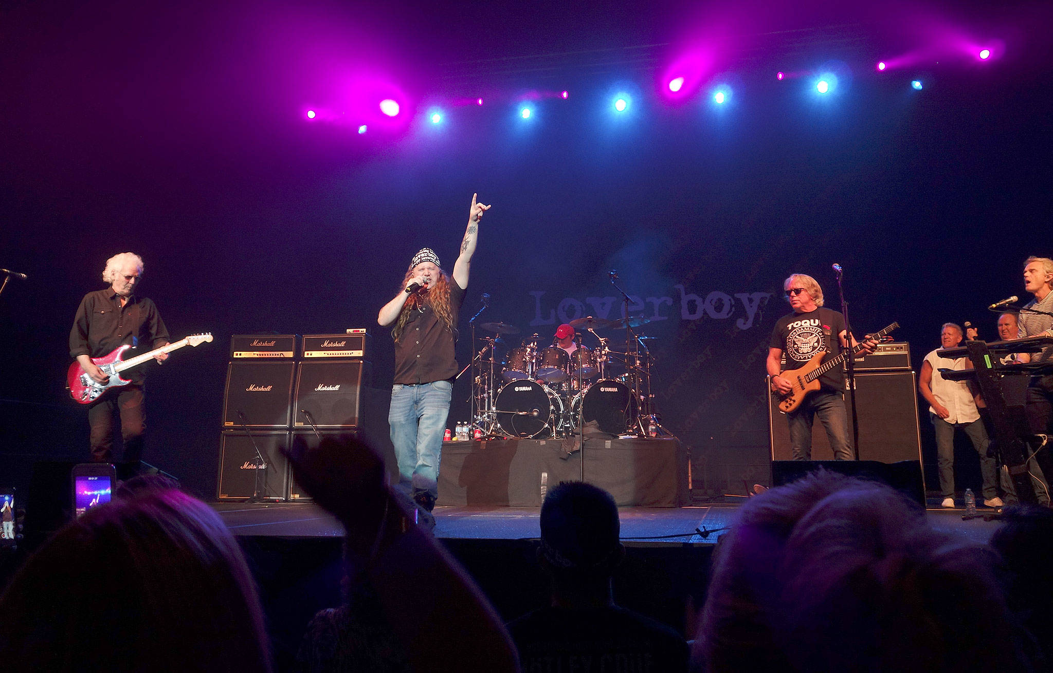 Steve Fournier raises his hand as he sings with the band Loverboy, whose lead singer, Mike Reno, announced he was too sick to continue after a couple of songs, at Xfinity Arena on Friday. (Courtesy photo)