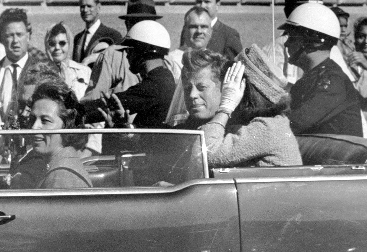 In this Nov. 22, 1963 photo, President John F. Kennedy waves from his car in a motorcade approximately one minute before he was shot in Dallas. Riding with Kennedy are First Lady Jacqueline Kennedy (right), Nellie Connally (second from left) and her husband, Texas Gov. John Connally (far left). (AP Photo/Jim Altgens, File)