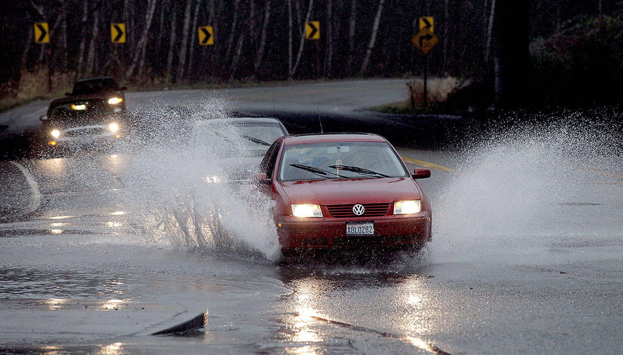 A driver navigates his way through standing water at the intersection of Ash Way and Maple Road near the Alderwood mall during afternnoon rain in 2011. (Herald file)