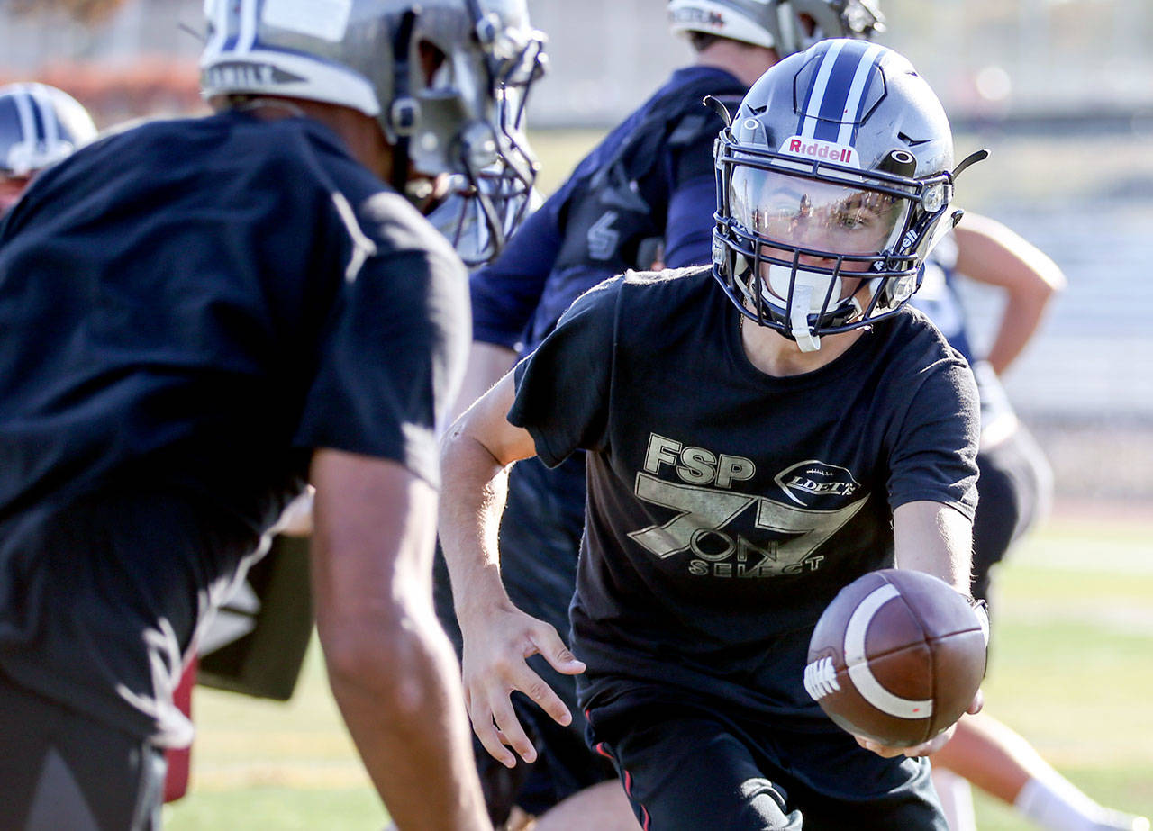 Glacier Peak quarterback Ayden Ziomas hands off the ball during practice Sept. 27, 2017, at Glacier Peak High School in Snohomish. (Kevin Clark / The Herald)