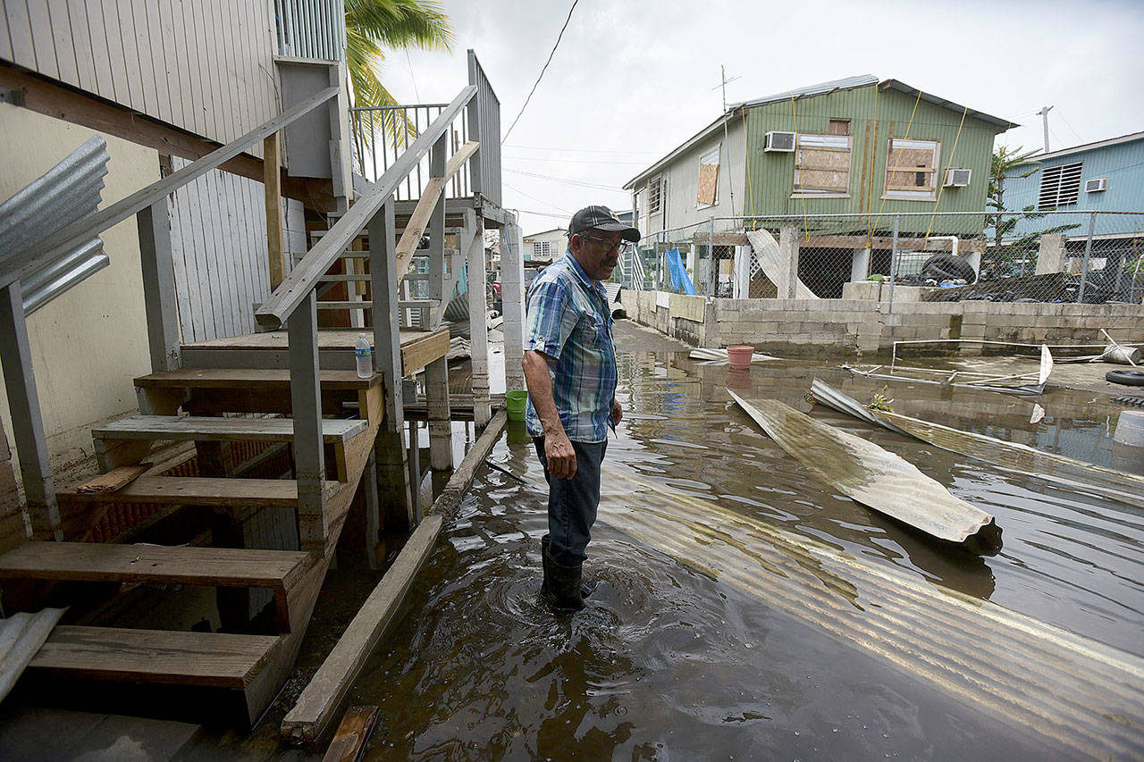 Juana Matos resident Hector Rosa walks through a flooded area after Hurricane Maria in Puerto Rico on Wednesday. (AP Photo/Carlos Giusti)