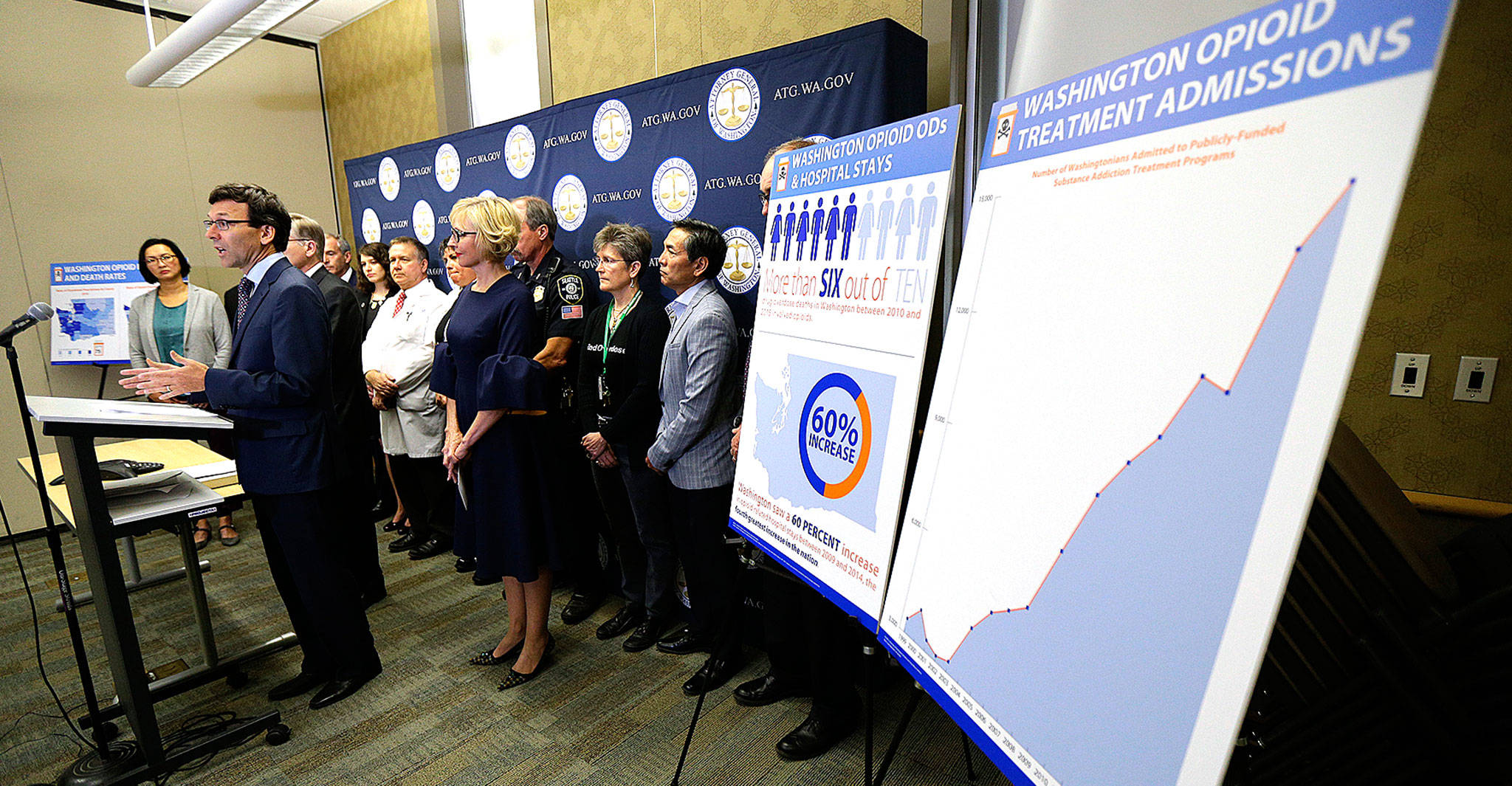 Washington Attorney General Bob Ferguson (second from left) talks to reporters Thursday in Seattle about the state and the city filing lawsuits against several makers of opioids, including Purdue Pharma. (Ted S. Warren / AP)