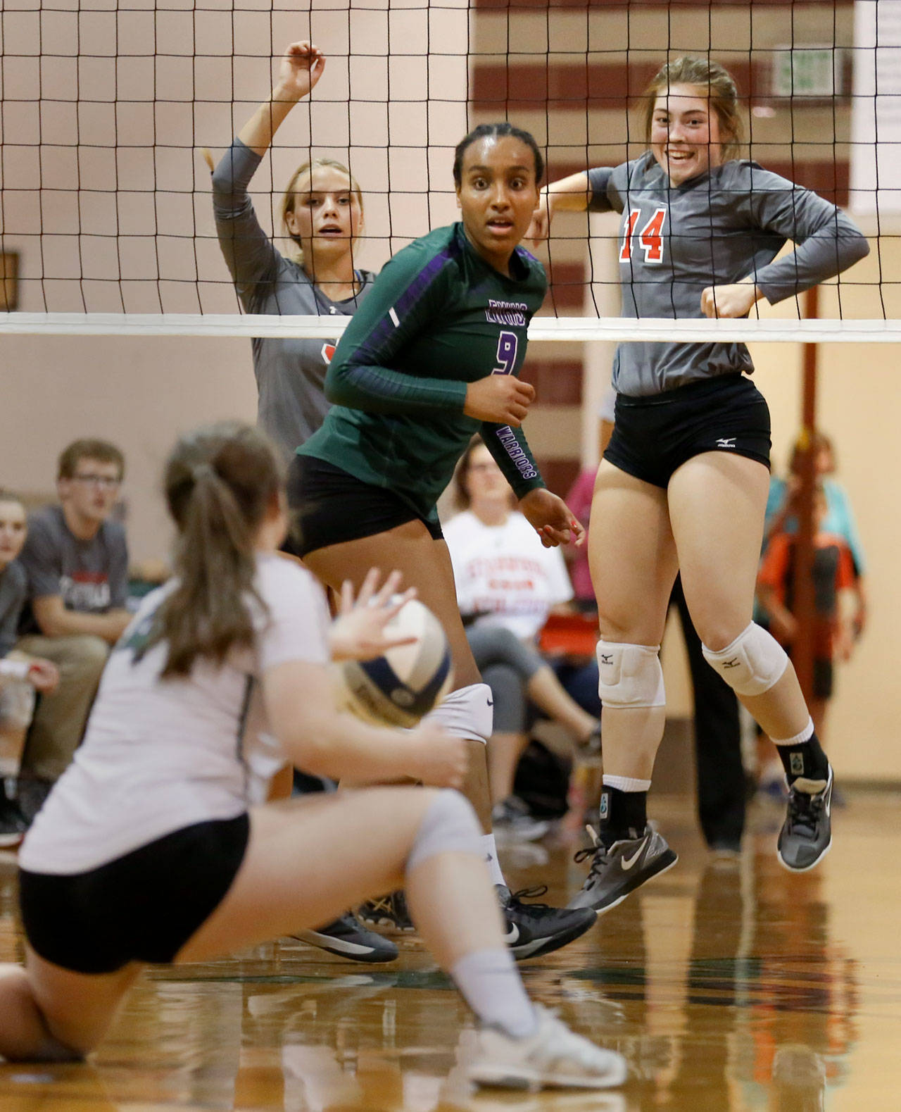 Stanwood’s Emma Bash (far right) and Saylor Anderson (far left) celebrate a kill with Edmonds-Woodway’s Betty Abraham (center) and Sam Hardan looking on during a match Sept. 28, 2017, at Edmonds-Woodway High School. Stanwood won in straight sets. (Kevin Clark / The Herald)