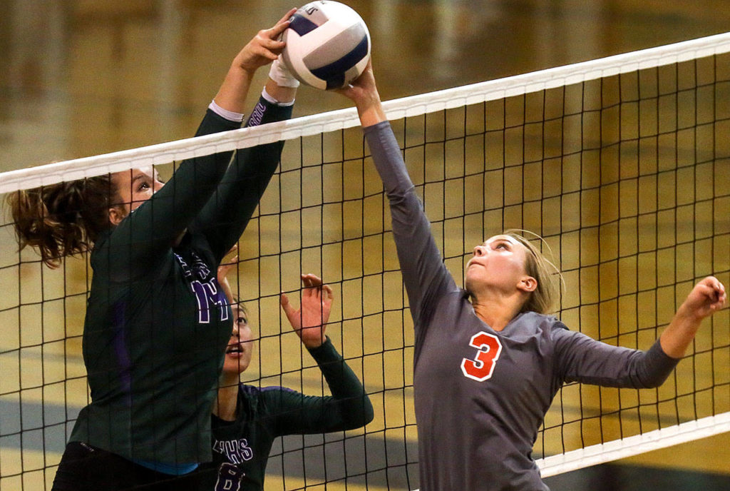 Edmonds-Woodway’s Bella Ygelsias (left) and Stanwood’s Saylor Anderson contest a point at the net with Edmonds-Woodway’s Sandra Yang (center) looking on during a match Sept. 28, 2017, at Edmonds-Woodway High School. Stanwood won in straight set. (Kevin Clark / The Herald)
