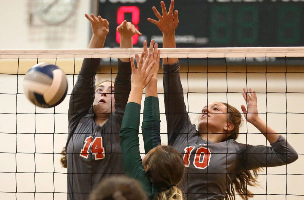 Stanwood’s Emma Bash (left) and Stanwood’s Taylor Lamb block Edmonds-Woodway’s Elizabeth Perenchio during a match Sept. 28, 2017, at Edmonds-Woodway High School. Stanwood won in straight set. (Kevin Clark / The Herald)
