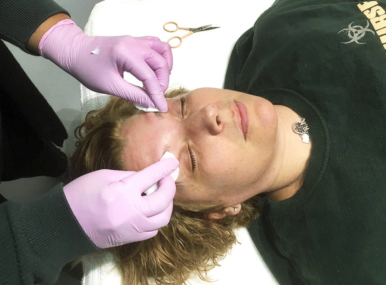 Tiffany Johnson came in for a quick eyebrow waxing job at Waxology, which offers whole-body waxing services for men and women. Walker puts salve on her brows to soothe the skin after the waxing. (Sue Misao / The Herald)