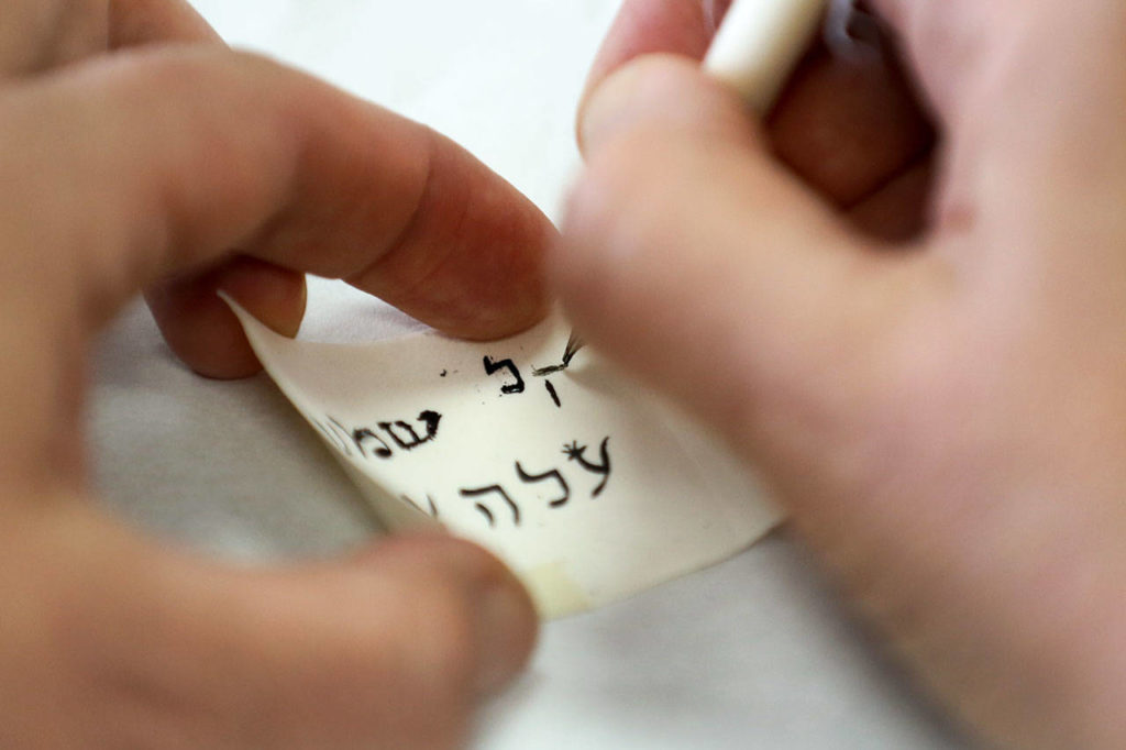 A workshop participant tries their at hand as a scribe using a quill and parchment at Chabad Center of Snohomish County in Lynnwod on Sept. 10. (Kevin Clark / The Herald)
