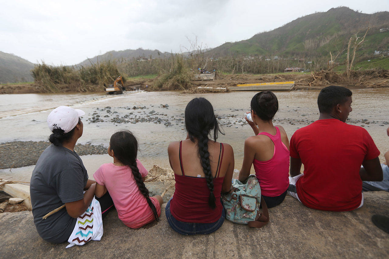 People on both sides sit on the edge of a destroyed bridge that crossed the San Lorenzo de Morovis River, in the aftermath of Hurricane Maria, in Morovis, Puerto Rico, on Wednesday. More than a week since the passing of Maria many are still waiting for help from from the federal and Puerto Rican governments. But the scope of the devastation is so broad, and the relief effort so concentrated in San Juan, that many people outside of the capital say they have received little to no help. (Gerald Herbert/Associated Press)