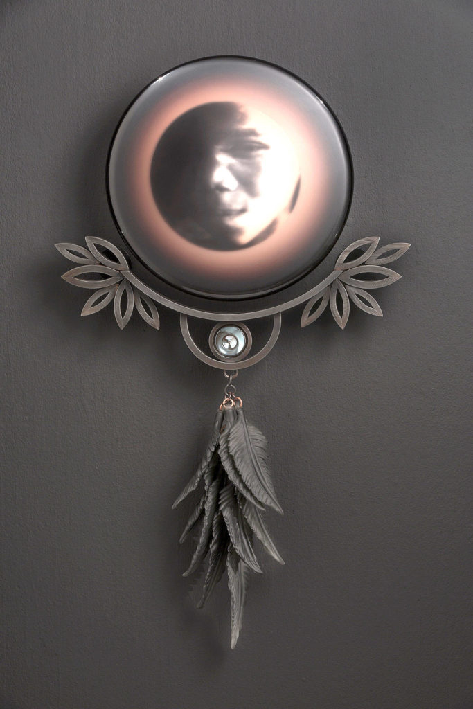 Exhibited currently at the Schack in Everett is “Child, Namibia” 2016 — original photo image; screen-printed, kiln-fired, blown, sculpted, sandblasted, found and mirrored glass; copper; steel with patina.
