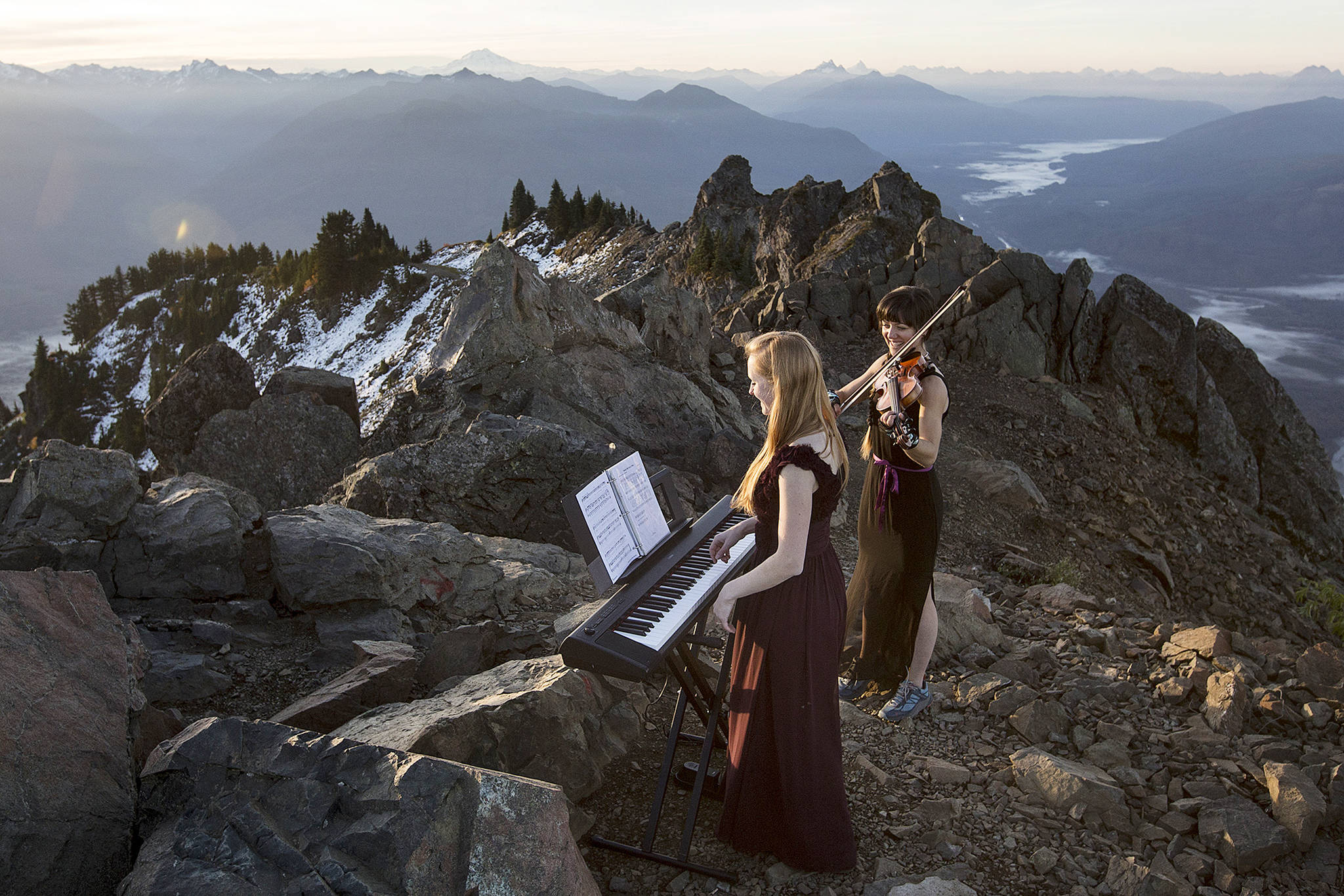 Rose Freeman (center) and Anastasia Allison play atop Sauk Mountain near Concrete on Oct. 5. The pair play violin and piano together at sunrise across the Cascades under the name The Musical Mountaineers. (Ian Terry / The Herals)
