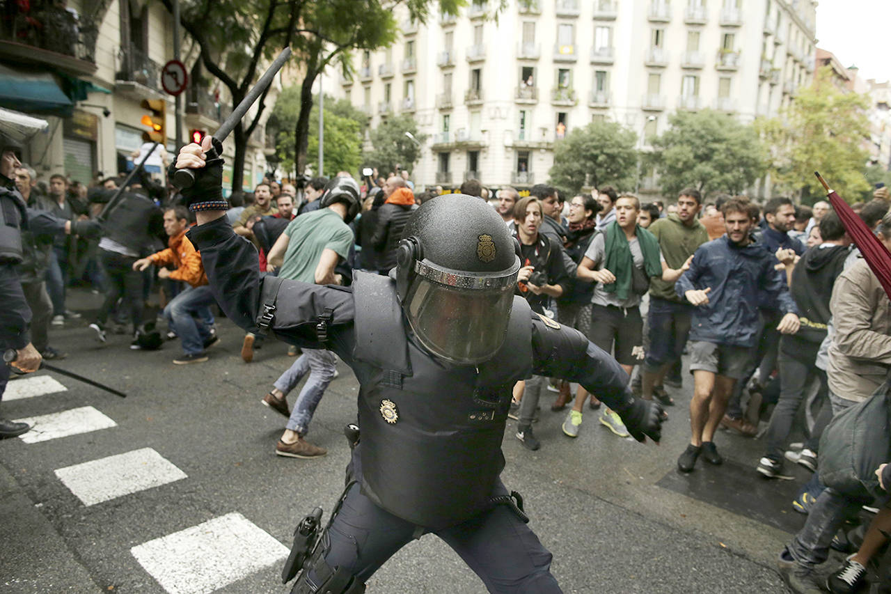Spanish riot police swings a club against would-be voters near a school assigned to be a polling station by the Catalan government in Barcelona, Spain, on Sunday. (AP Photo/Manu Fernandez)