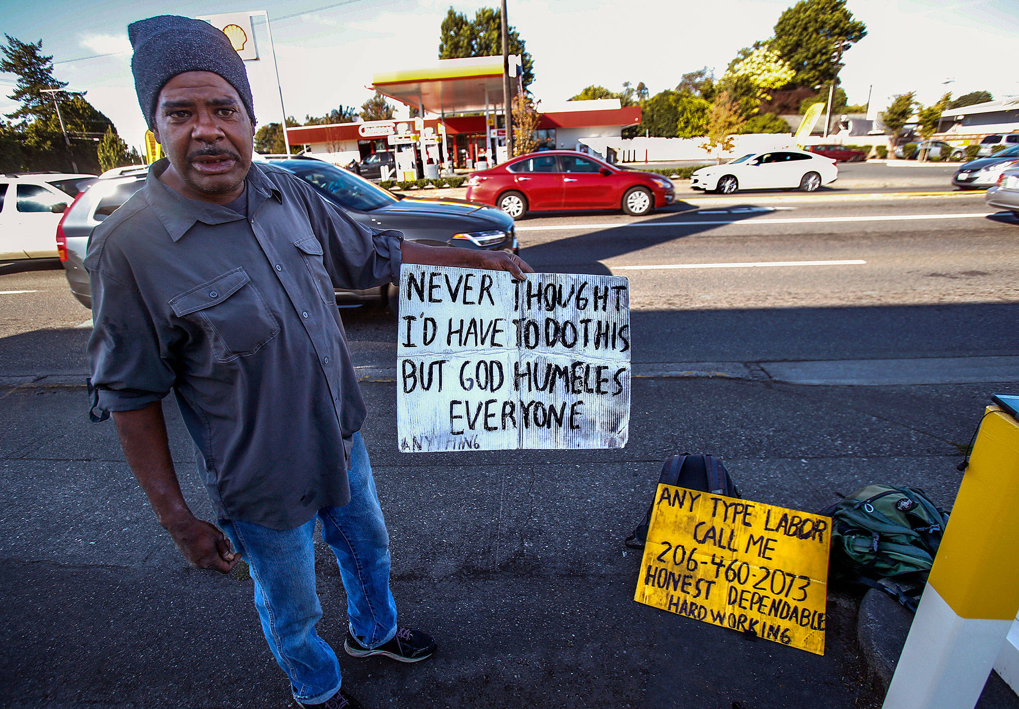 In Marysville, a 48-year-old man, who says people will know as “Houston,” pulls his signs from his backpack and talks to The Herald about surviving homelessness. (Dan Bates / The Herald)